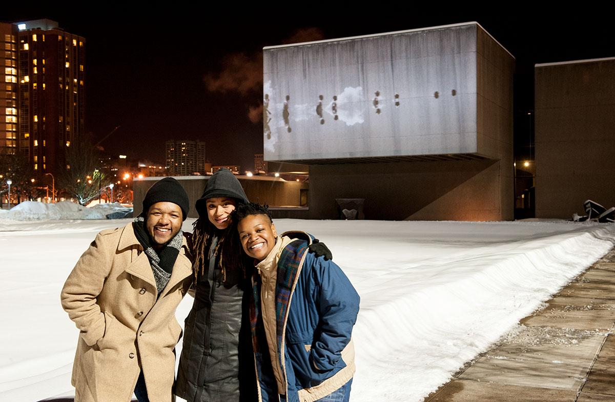 Black Radical Imagination Curators Amir George (left) and Erin Christovale (right) with featured artist Jeannette Ehlers (center) with UVP Everson projection of Ehlers' </em>Black Bullets</em>.