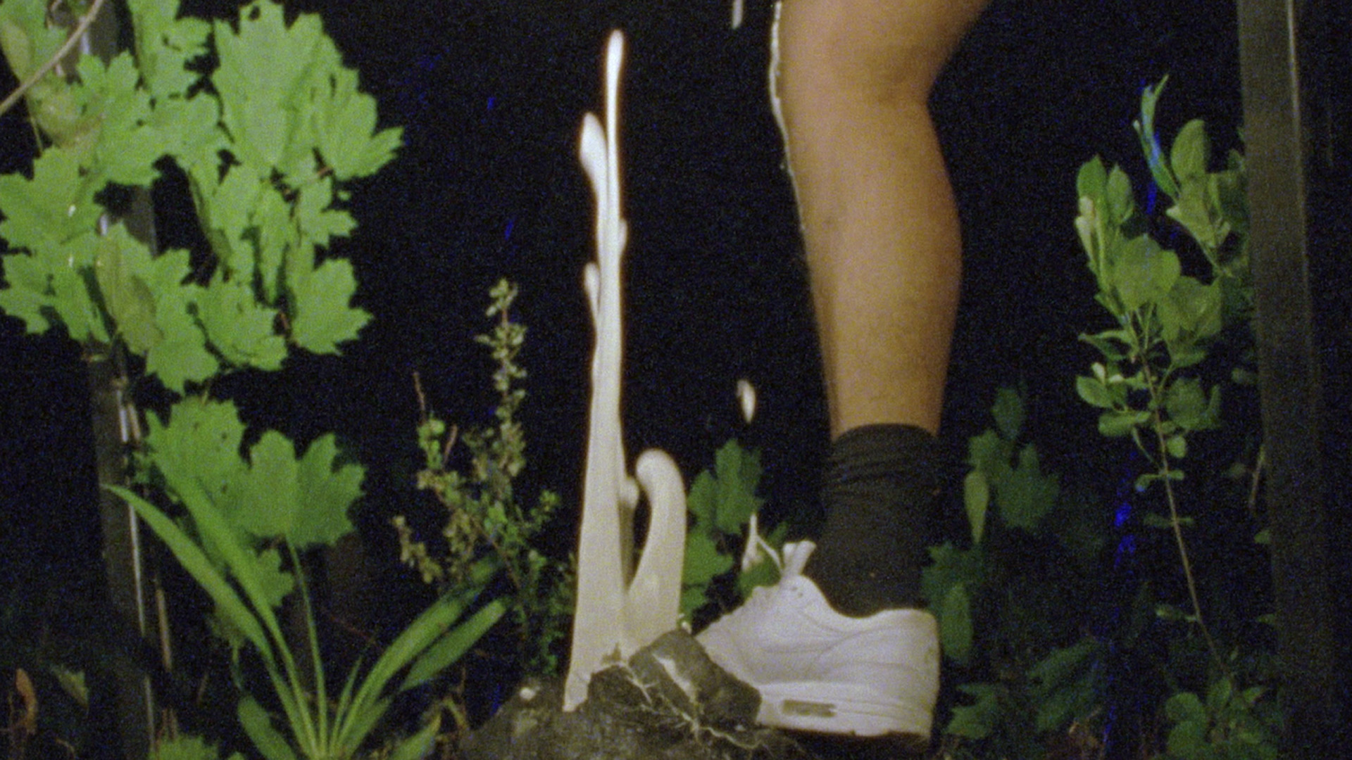Foot stamping and white viscous liquid seems to flow up defying gravity in still from (2020) by Luis Arnias